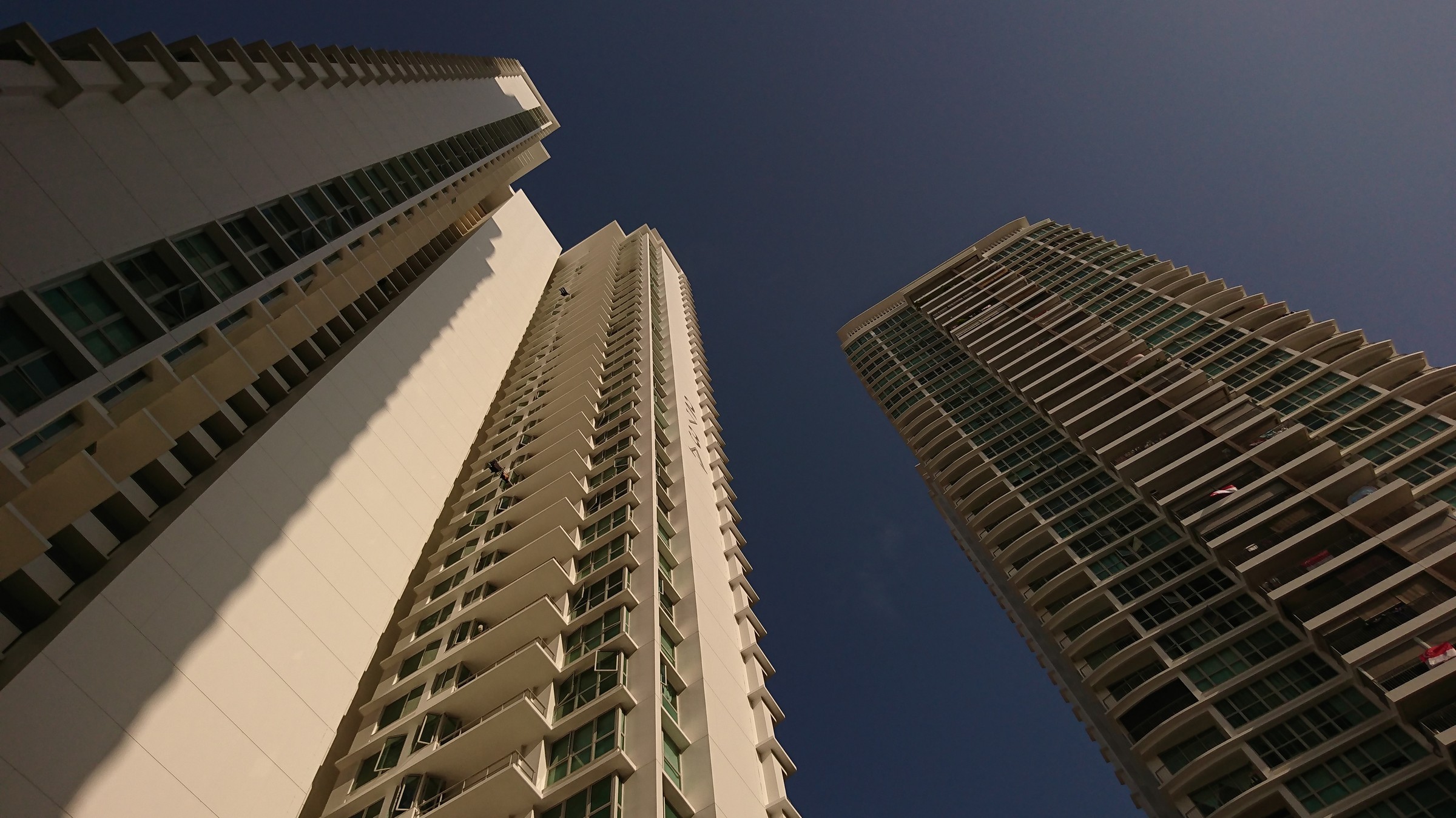 Looking up at the three 40-storey towers of Natura Loft, a DBSS development at Bishan Street 24, against a clear sky.