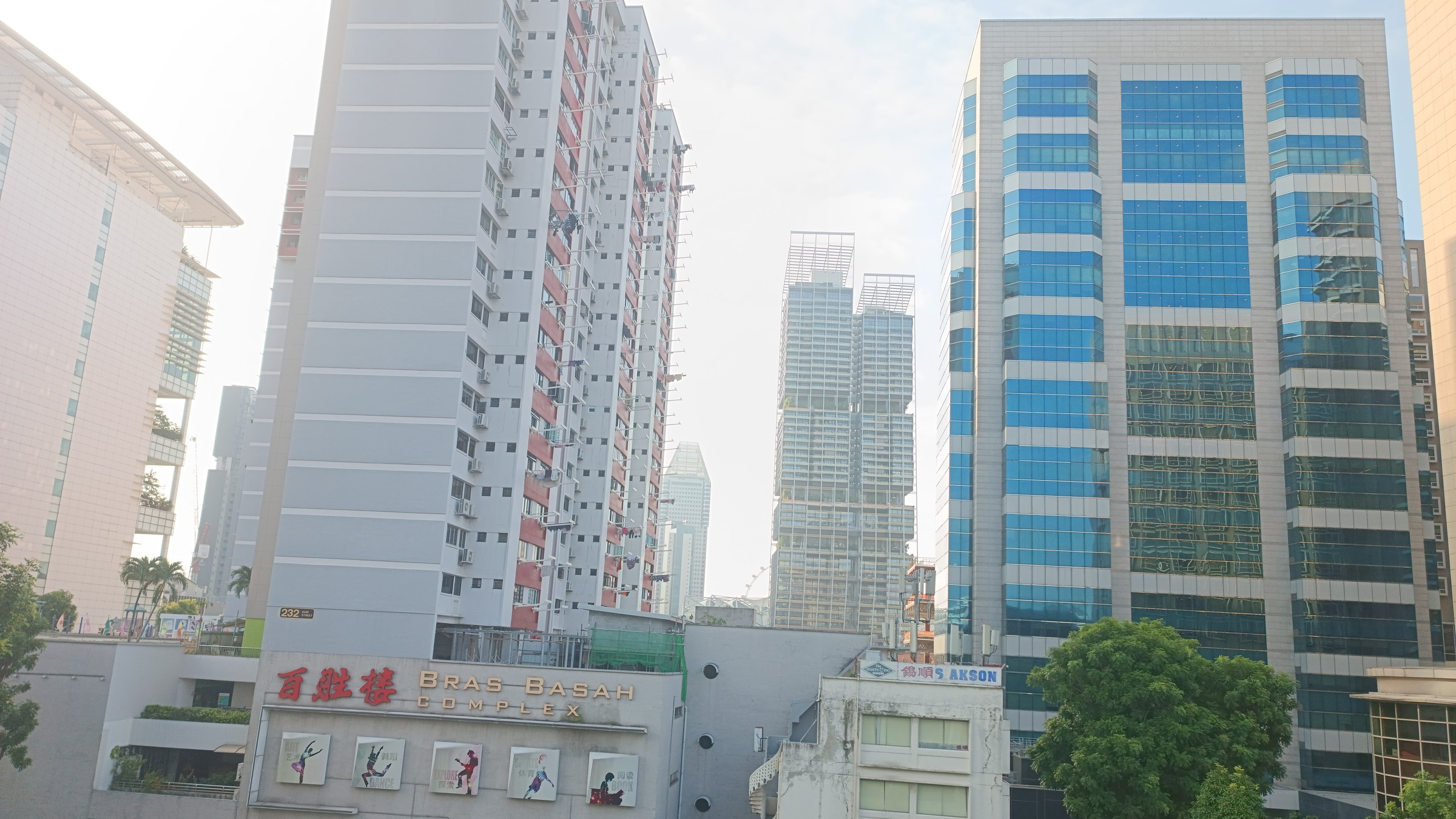 Bras Basah Complex with its signage visible, flanked by office towers, photographed from street level.