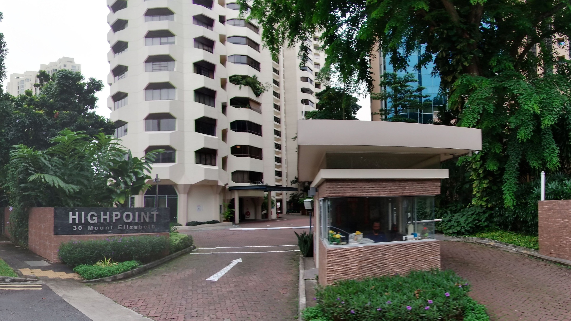 The driveway entrance of High Point condominium at 30 Mount Elizabeth, with its brick estate sign, guardhouse and the cream tower's faceted balconies.