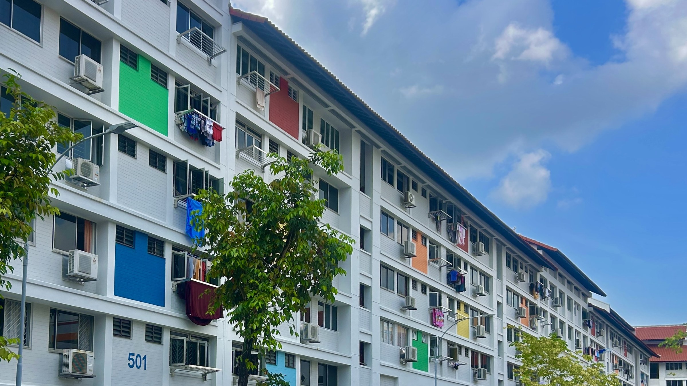 A white HDB block in Bishan with colourful laundry hanging from its windows.