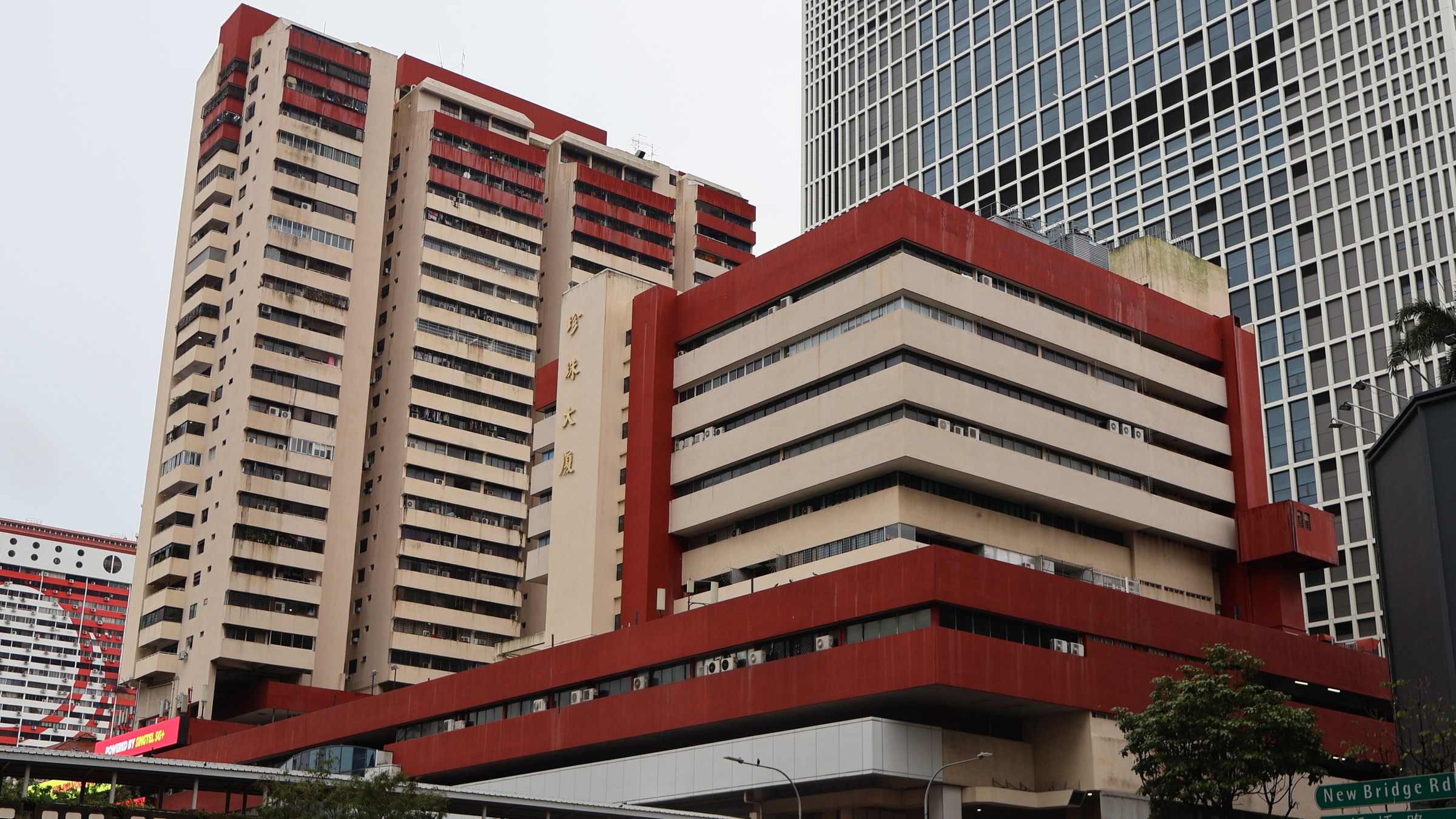 People's Park Centre's red and cream residential towers and podium at the corner of New Bridge Road in Chinatown, Singapore.