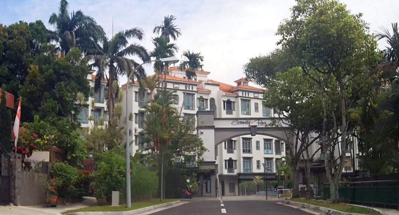 Arched entrance gateway bearing the Serenity Park name, with the condominium's white five-storey blocks behind.