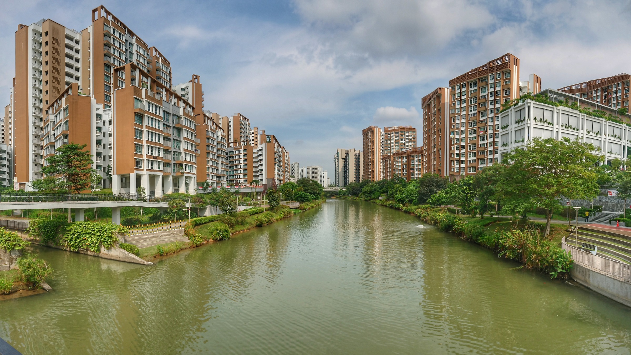 Modern HDB blocks lining both sides of the Punggol Waterway on a clear day.